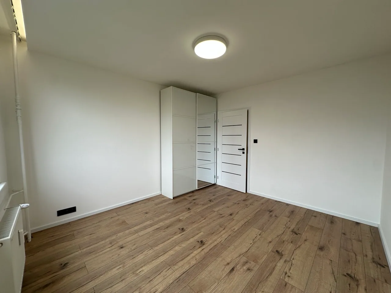 Prázdný pokoj s novou podlahou a vestavěnou skříní
