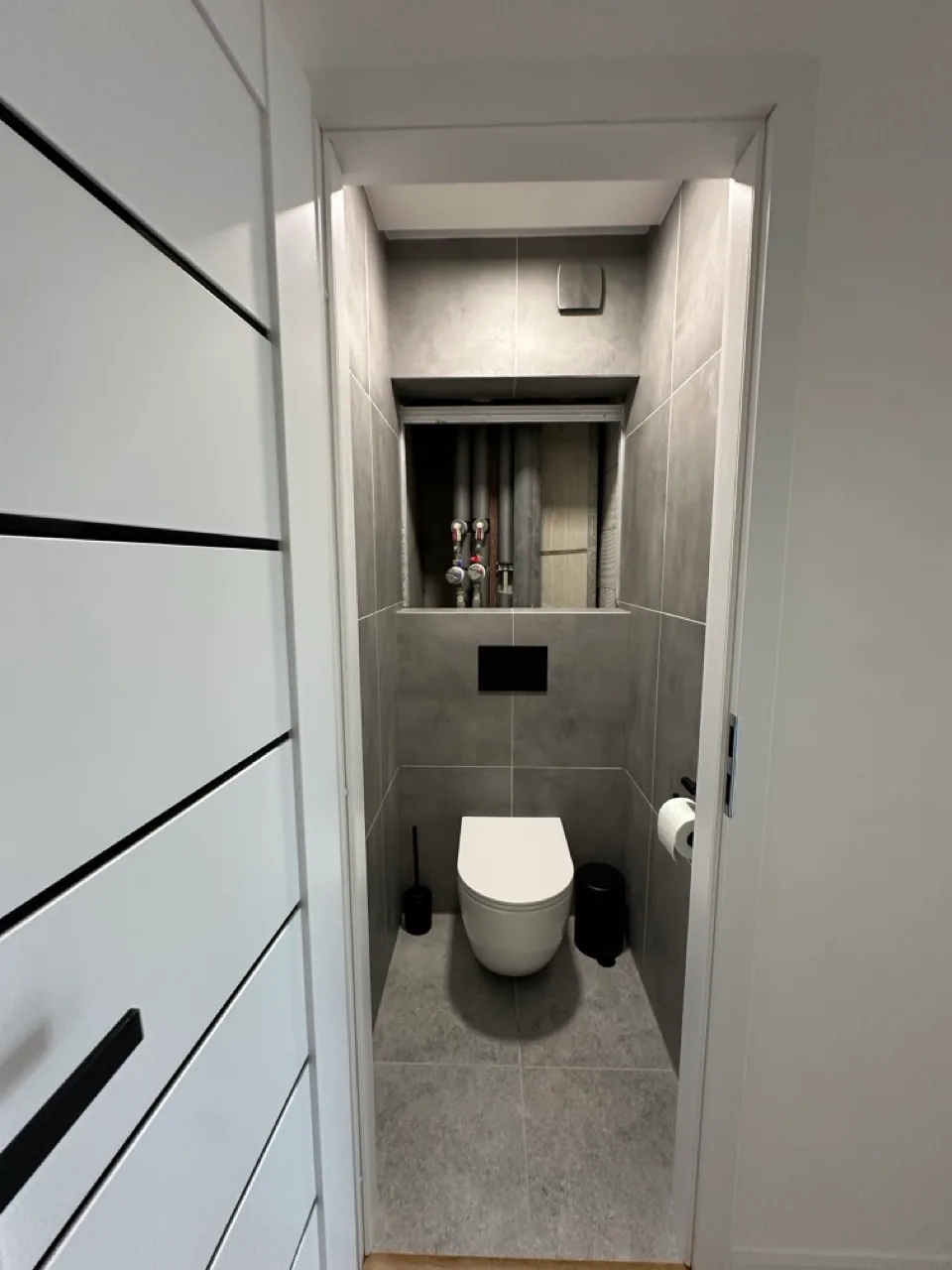 Samostatné WC s šedým obkladem a závěsnou toaletou